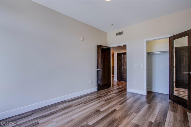 8925 W Flamingo Rd Unit 228, Las Vegas, NV 89147 - unfurnished bedroom featuring baseboards, visible vents, a closet, and wood finished floors