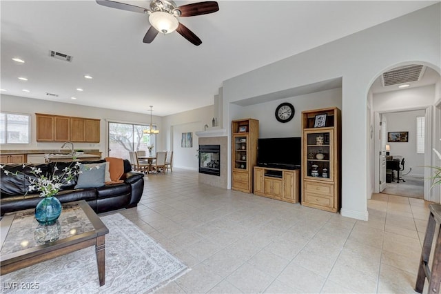 living area featuring arched walkways, light tile patterned floors, visible vents, and a ceiling fan