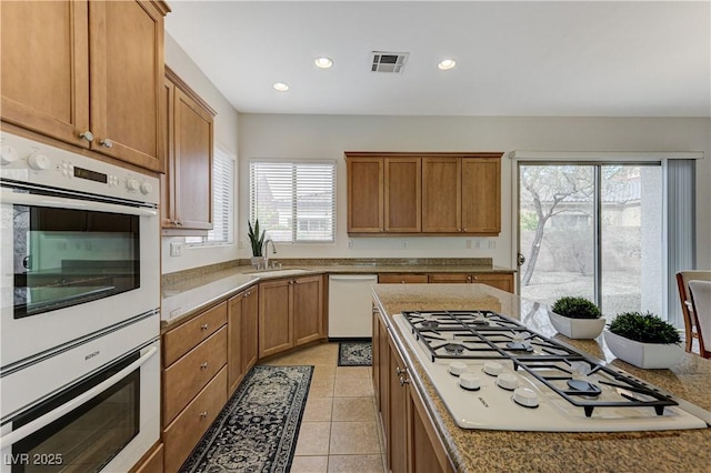 kitchen featuring plenty of natural light, white appliances, visible vents, and a sink