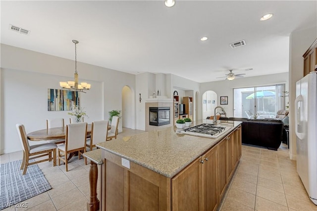 kitchen with stainless steel gas cooktop, arched walkways, freestanding refrigerator, and visible vents