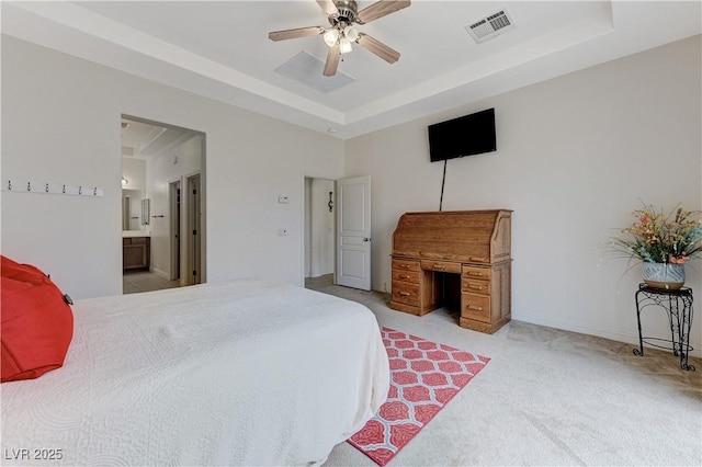 carpeted bedroom with visible vents, ceiling fan, a tray ceiling, and ensuite bath