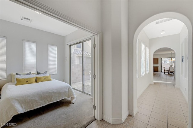 bedroom with arched walkways, light tile patterned floors, visible vents, and multiple windows