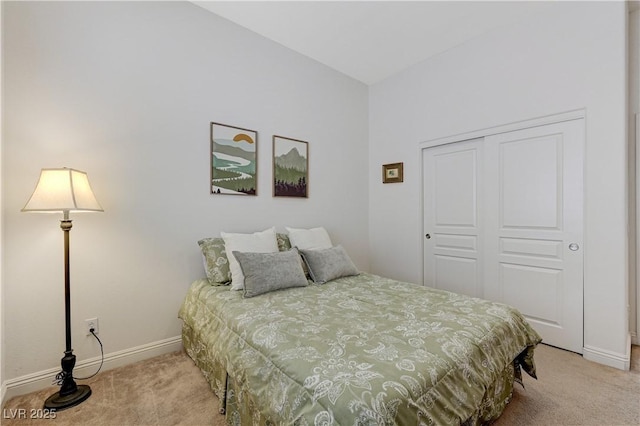 bedroom with a closet, light colored carpet, and baseboards