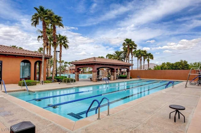community pool with a patio and fence