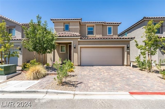 mediterranean / spanish home featuring a tile roof, decorative driveway, stucco siding, and an attached garage