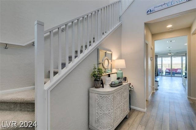 stairway with baseboards, wood finished floors, and recessed lighting