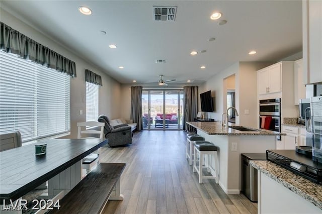 kitchen featuring a sink, double oven, open floor plan, light wood-type flooring, and visible vents