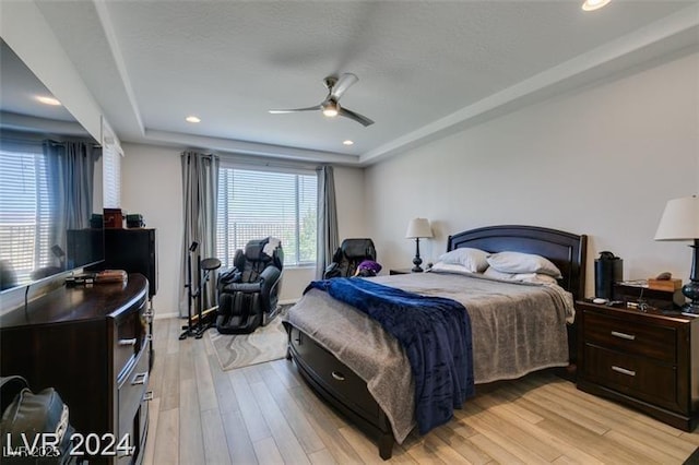 bedroom featuring ceiling fan, recessed lighting, light wood-type flooring, and a raised ceiling