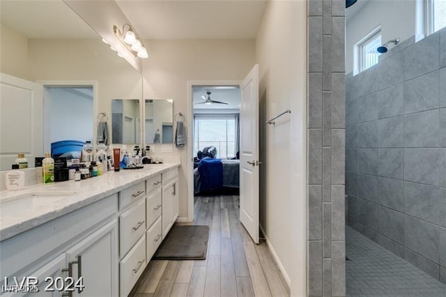 ensuite bathroom featuring connected bathroom, a walk in shower, wood tiled floor, ceiling fan, and double vanity
