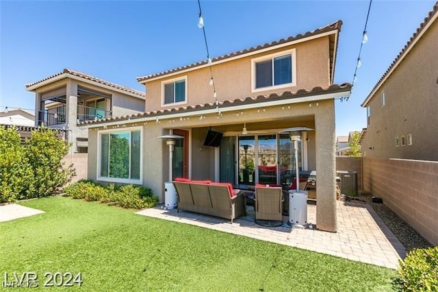 rear view of property with stucco siding, fence, a yard, and a patio area