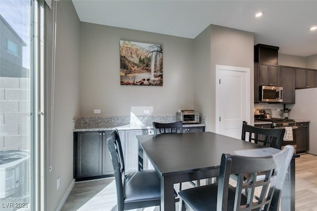 dining room featuring baseboards, recessed lighting, and light wood-style flooring