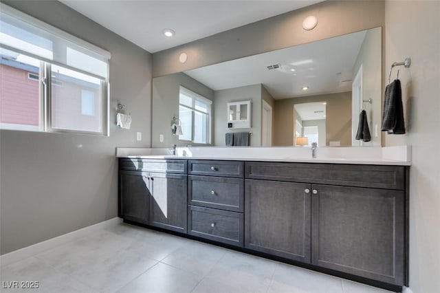full bath with a sink, double vanity, tile patterned floors, baseboards, and visible vents