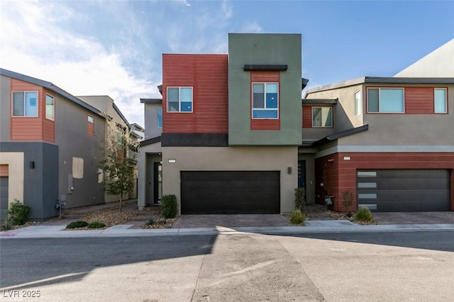 modern home with stucco siding, an attached garage, and driveway
