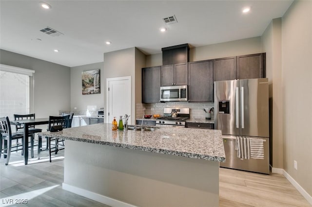 kitchen featuring stainless steel appliances, visible vents, decorative backsplash, and a sink