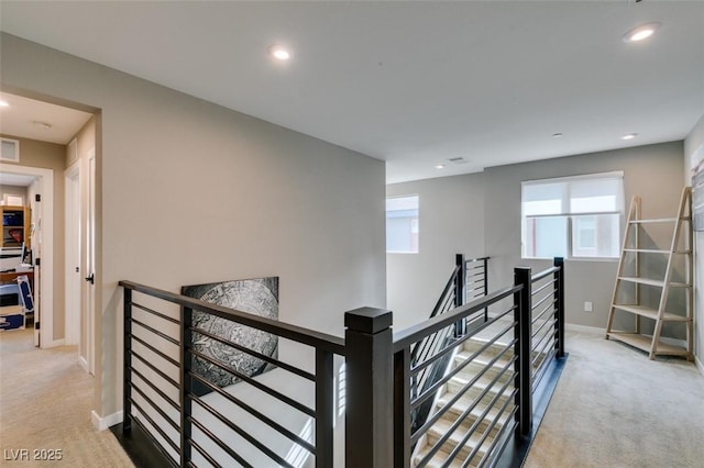 hall featuring carpet floors, recessed lighting, and an upstairs landing