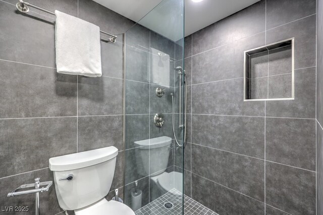 bathroom featuring a tile shower and toilet