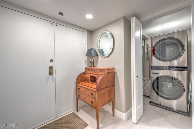 laundry area with baseboards, stacked washer / dryer, laundry area, and light tile patterned floors