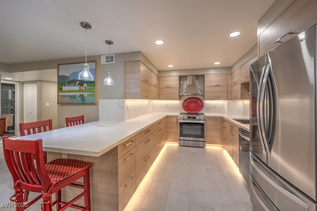 kitchen with light brown cabinets, wall chimney range hood, modern cabinets, and appliances with stainless steel finishes