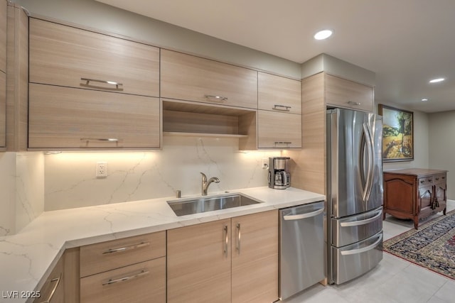 kitchen with backsplash, appliances with stainless steel finishes, a sink, and light brown cabinetry