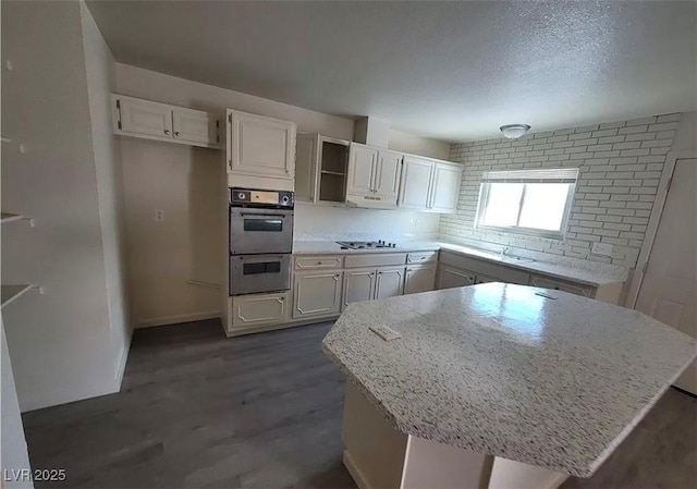 3749 Ponderosa Ave, Las Vegas, NV 89115 - kitchen featuring white cabinetry, open shelves, dark wood-style flooring, gas stovetop, and light stone counters