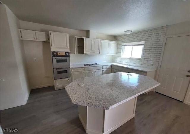 3749 Ponderosa Ave, Las Vegas, NV 89115 - kitchen with gas cooktop, dark wood-style floors, double oven, and white cabinets