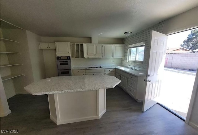 3749 Ponderosa Ave, Las Vegas, NV 89115 - kitchen featuring white cabinetry, a center island, double oven, a sink, and light stone counters