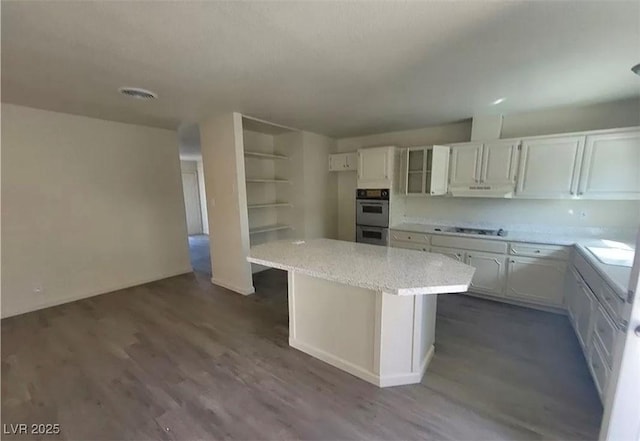 3749 Ponderosa Ave, Las Vegas, NV 89115 - kitchen with double oven, a center island, under cabinet range hood, white cabinets, and dark wood-type flooring