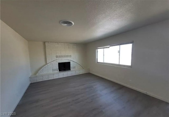 3749 Ponderosa Ave, Las Vegas, NV 89115 - unfurnished living room with a fireplace, dark wood-style floors, a textured ceiling, and visible vents