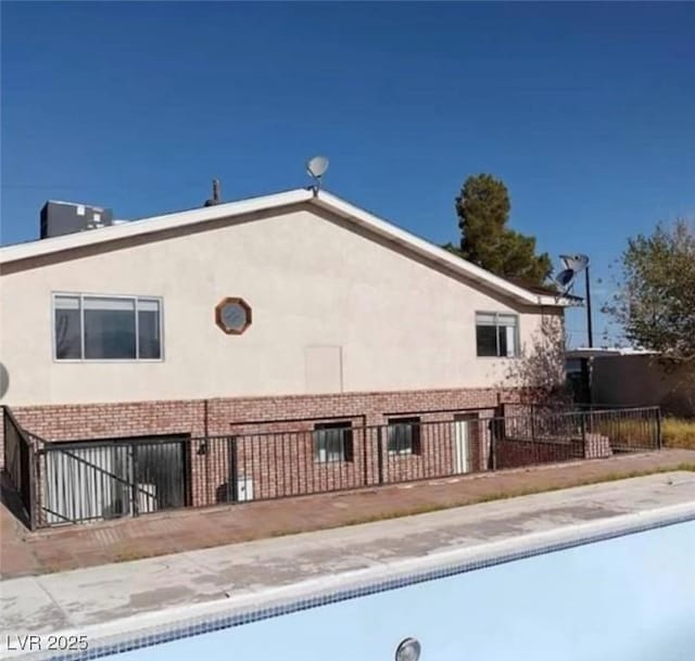 664 Sky Rd, Indian Springs, NV 89018 - rear view of house featuring stucco siding, an attached garage, fence, and brick siding