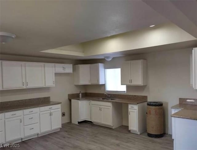 664 Sky Rd, Indian Springs, NV 89018 - kitchen with light wood finished floors, white cabinets, a sink, and a raised ceiling