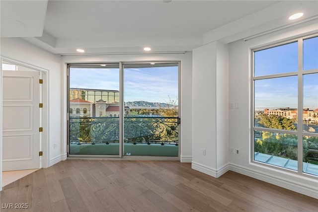 empty room featuring recessed lighting, baseboards, wood finished floors, and plenty of natural light