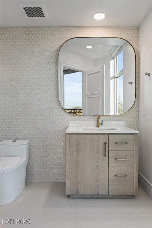 half bath with visible vents, recessed lighting, vanity, and toilet