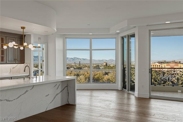 kitchen with hardwood / wood-style floors, light stone counters, a sink, decorative light fixtures, and a mountain view