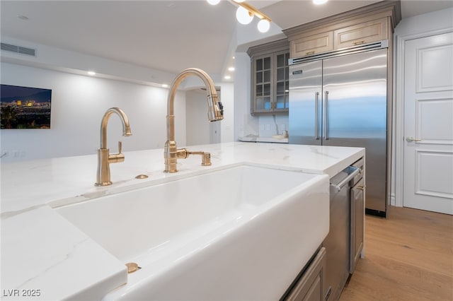 details with wood finished floors, a sink, stainless steel built in refrigerator, visible vents, and recessed lighting