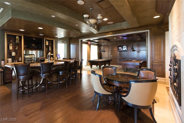 dining space featuring wood finished floors, a decorative wall, pool table, and indoor wet bar