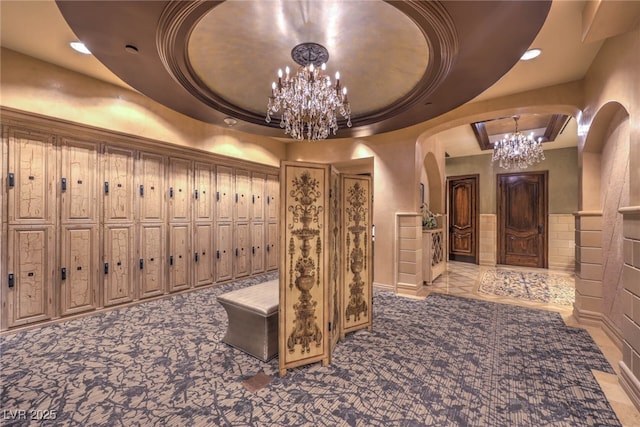 wine cellar with recessed lighting, arched walkways, a notable chandelier, and a raised ceiling