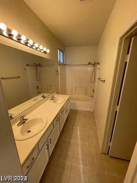 bathroom with double vanity, bathtub / shower combination, and a sink