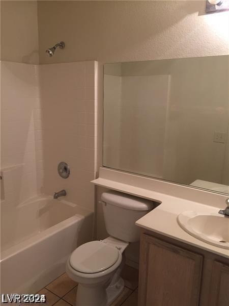 full bath featuring vanity, toilet, a textured wall, tile patterned floors, and shower / bathtub combination