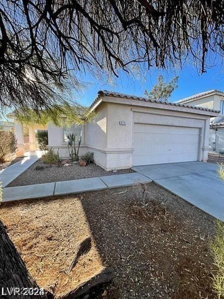 view of property exterior featuring a tiled roof, a garage, driveway, and stucco siding