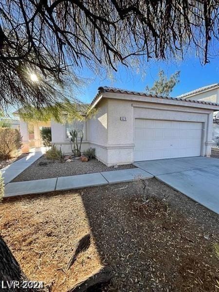 view of side of property featuring driveway, stucco siding, a garage, and a tiled roof