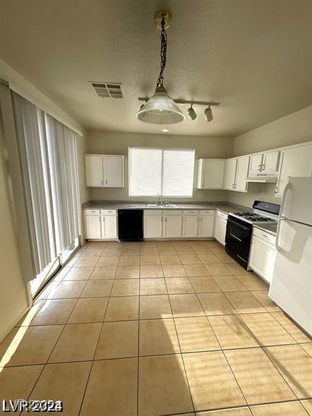 kitchen featuring range with gas cooktop, a sink, visible vents, freestanding refrigerator, and black dishwasher