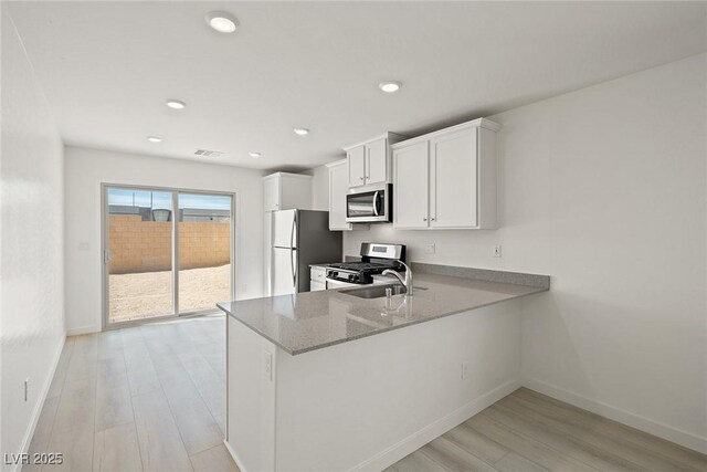 2618 Lily Point St, Las Vegas, NV 89156 - kitchen with stainless steel appliances, light wood-type flooring, baseboards, a sink, and white cabinetry