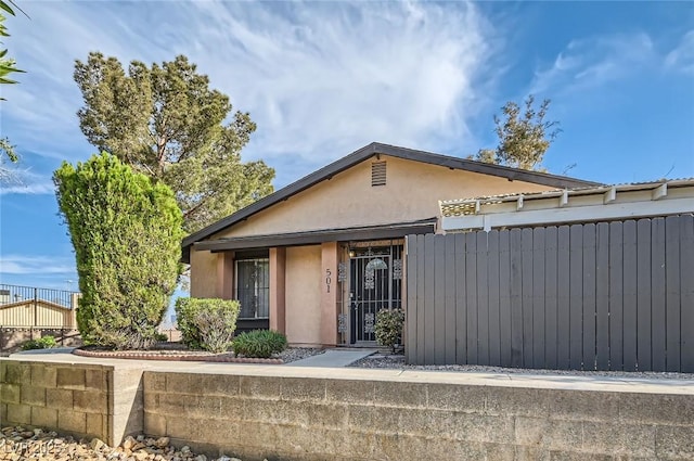 view of front of property featuring stucco siding and fence