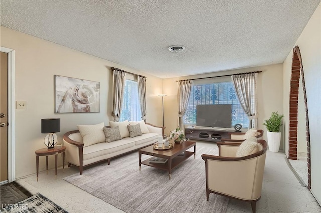 living area featuring plenty of natural light, visible vents, and a textured ceiling