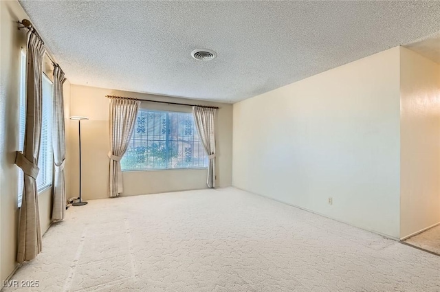 carpeted empty room with visible vents and a textured ceiling
