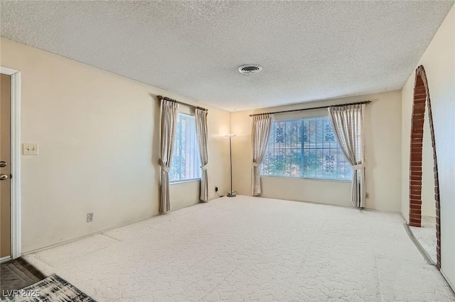 spare room featuring a textured ceiling, visible vents, and carpet floors