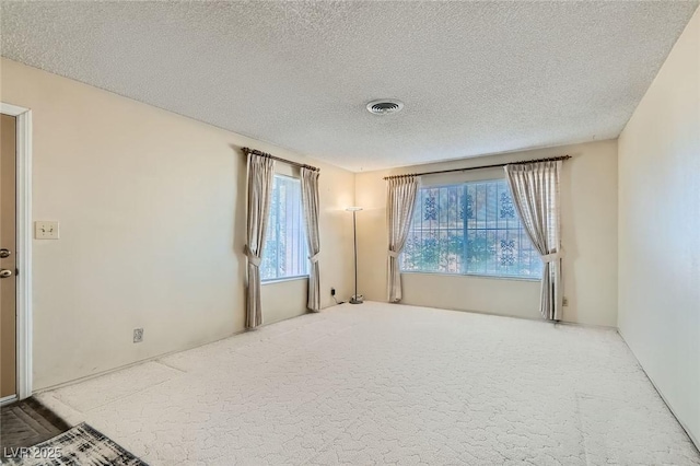 carpeted empty room with visible vents and a textured ceiling