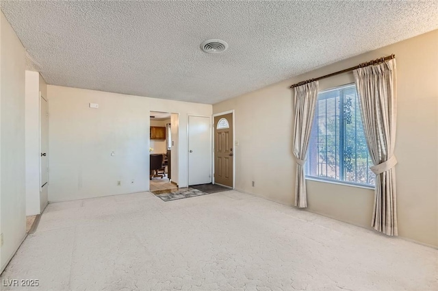 carpeted spare room with a textured ceiling and visible vents