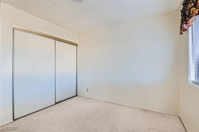 unfurnished bedroom with light carpet, a closet, and baseboards