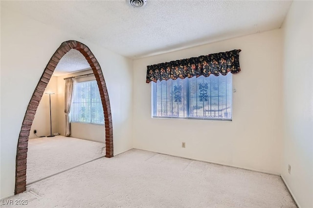 carpeted empty room featuring visible vents and a textured ceiling